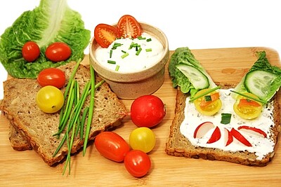 Holzbrett mit Brot, Gemüse und Quark: Gute Ernährung bedeutet auch Lebensqualität.