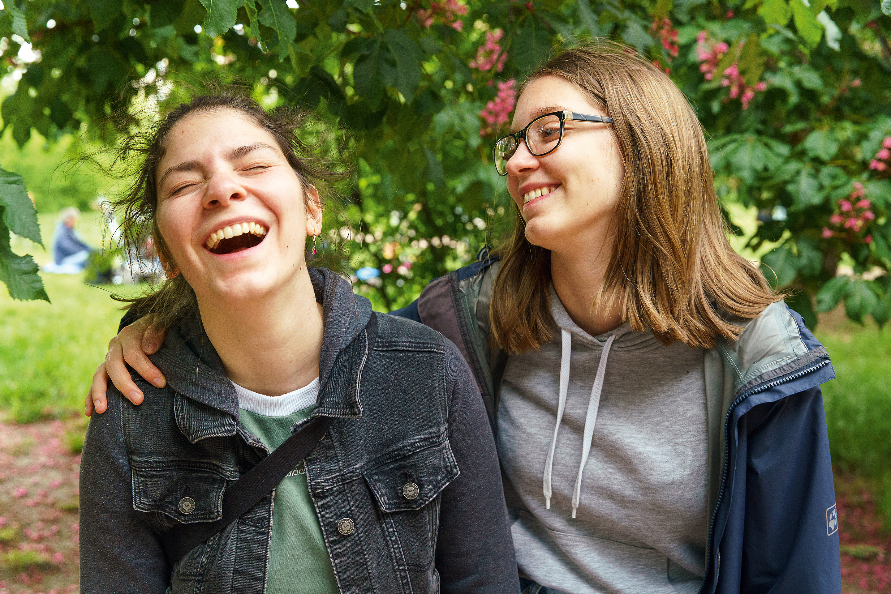 Zwei lachende Teenagerinnen, Arm in Arm.