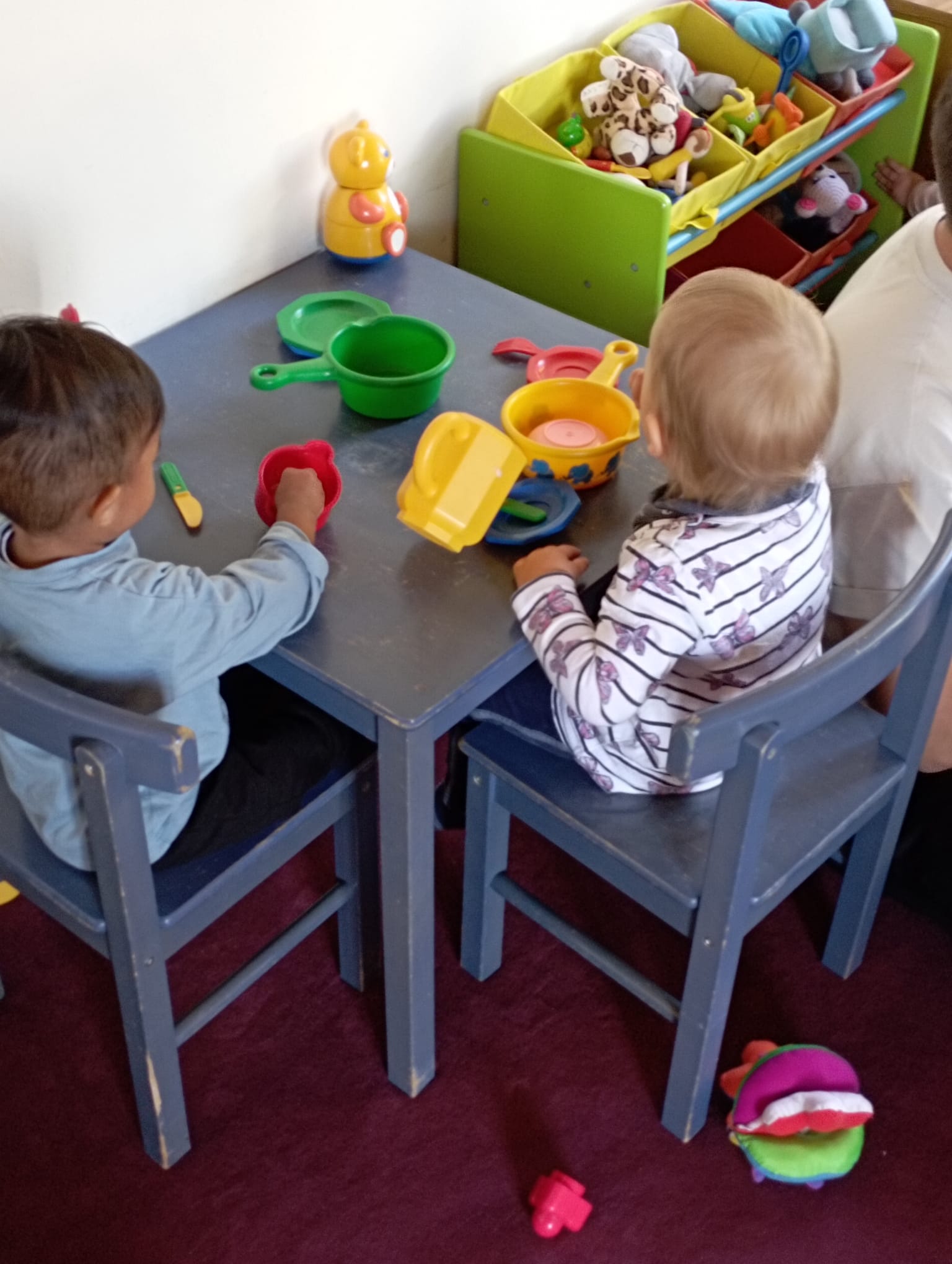 Zwei Kleinkinder spielen an einem Kindertisch gemeinsame Mahlzeit.